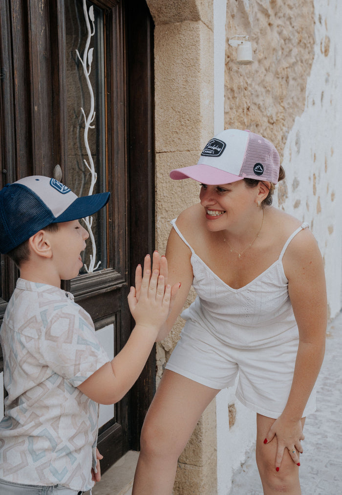 Woman and child wearing matching caps, standing close together outdoors.