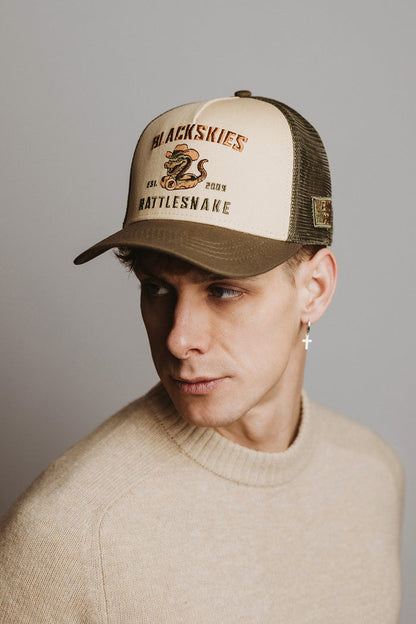 Man wearing a cap with a brand logo on a gray background